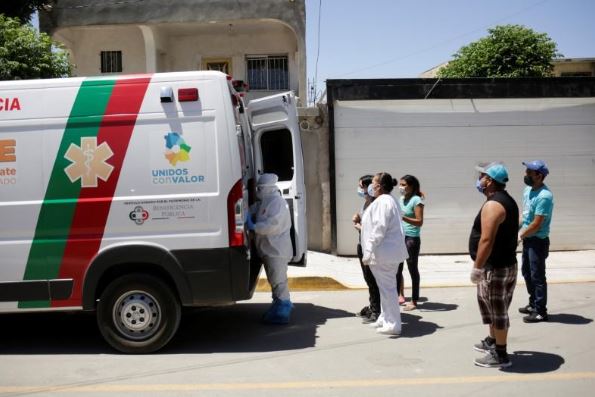 أقارب رجل توفي بفيروس كورونا قبل نقله إلى المستشفى بجوار سيارة إسعاف تنقل جثته يوم 26 مايو 2020. تصوير: خوسيه لويس جونزاليس - رويترز